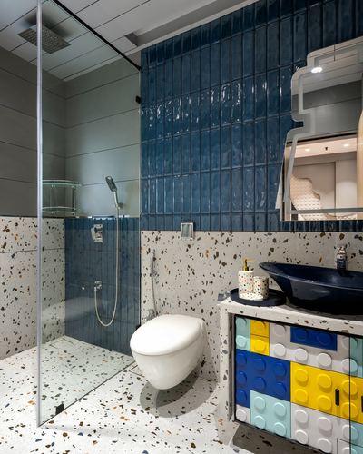 Bathroom with blue tiled shower, terrazzo walls, wall-hung toilet, and lego-print vanity cabinet