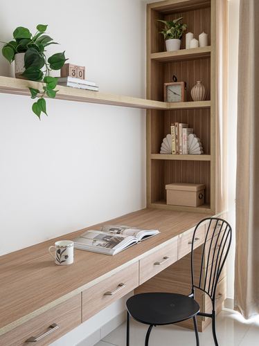 Wooden study desk with built-in shelving unit and black wire chair by a window