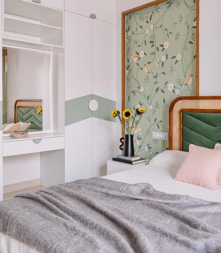 Bedroom with cane headboard, green velvet cushion, sunflower vase, and framed floral wallpaper panel