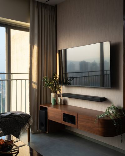 Living room with floating walnut console, mounted tv, and balcony view at sunset