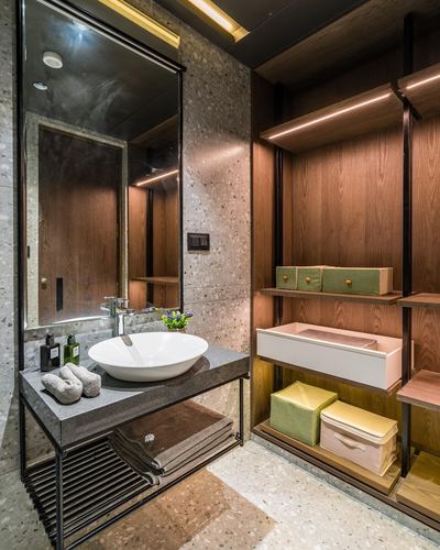 Terrazzo bathroom with black-framed mirror, stone vanity, and adjacent wood-toned open wardrobe shelving