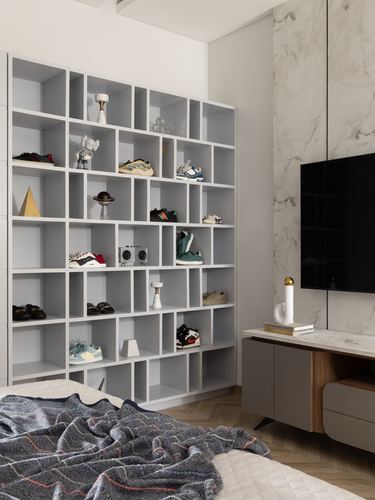 Grey cubby shelving displaying sneakers and figurines beside a marble-clad TV wall in a bedroom