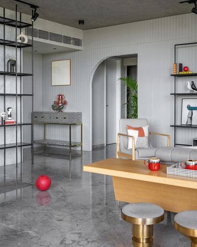 Grey-toned living room with arched doorway, brass-legged console, wooden coffee table and red accents