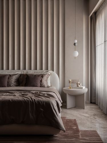 Bedroom with fluted tan upholstered wall, rounded bed, sculptural side table and globe pendant light