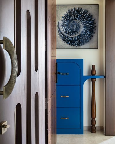 View through carved wooden door to a blue lacquered cabinet and turned wood console leg