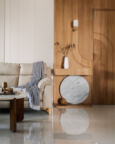 Living room corner with fluted wood paneling, round marble accent, cream sofa and throw