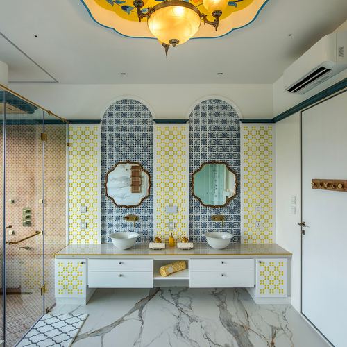 Symmetrical bathroom with blue-and-yellow tiled arches, two vessel sinks, and an ornate ceiling light