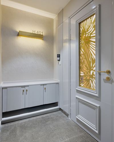 White entrance foyer with fluted console, brass sconce, and gold floral glass door panel