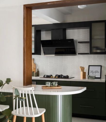 Green and white modern kitchen with black chimney hood and rounded island counter