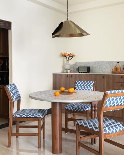 Round tiled dining table with ikat-patterned chairs under a brass cone pendant light