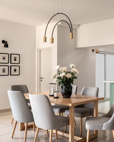 Dining room with wooden table, grey upholstered chairs, and arched black-and-brass pendant light