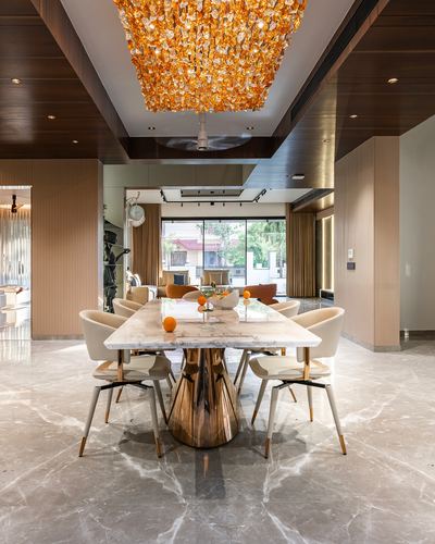 Dining room with marble table, brass pedestal base, and large amber chandelier overhead