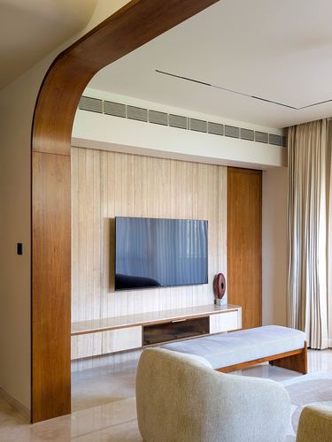 Curved wood archway framing a fluted stone tv wall with wooden console and bench