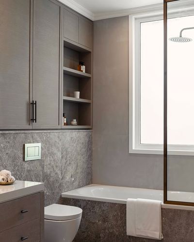 Grey minimalist bathroom with textured cabinetry, stone-look tile, tub, and glass shower partition