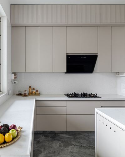 Modern greige kitchen with fluted upper cabinet, black hob, and speckled stone counters