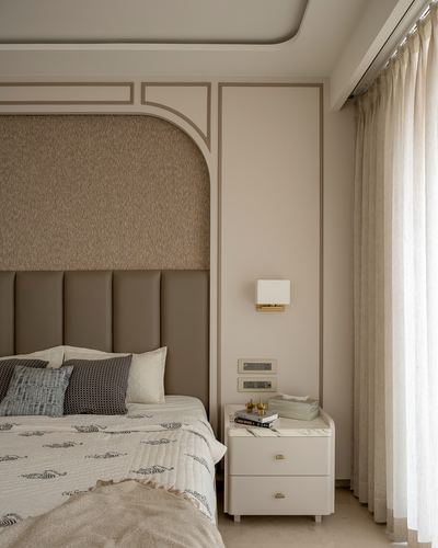 Beige bedroom with channel-tufted leather headboard, marble-top nightstand, and sheer curtains by window