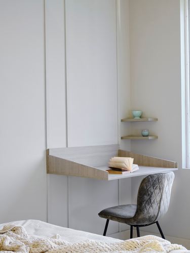 Wall-mounted wood desk with book, corner shelves, and quilted grey chair in minimal nook