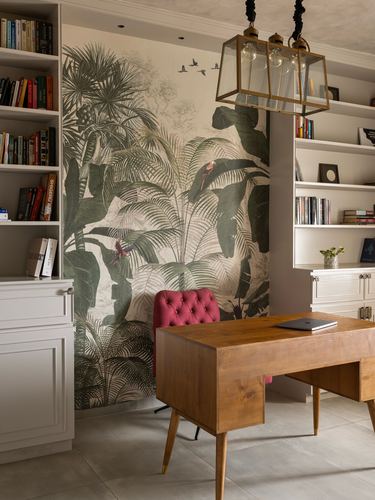 Study nook with tropical mural wall, white bookshelves, wooden desk and pink tufted chair