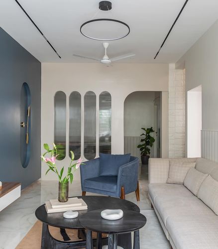 Living room with navy accent wall, arched fluted glass panels, and black nesting coffee tables on marble floor