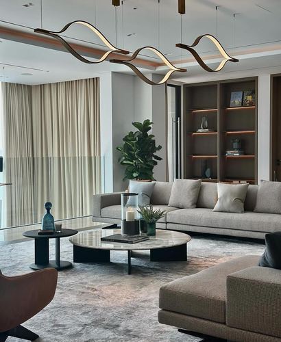 Modern living room with grey sofas, round marble coffee table, and wave-shaped pendant lights