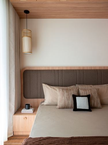 Bedroom corner with wood-panelled ceiling, cane pendant light and upholstered headboard bed