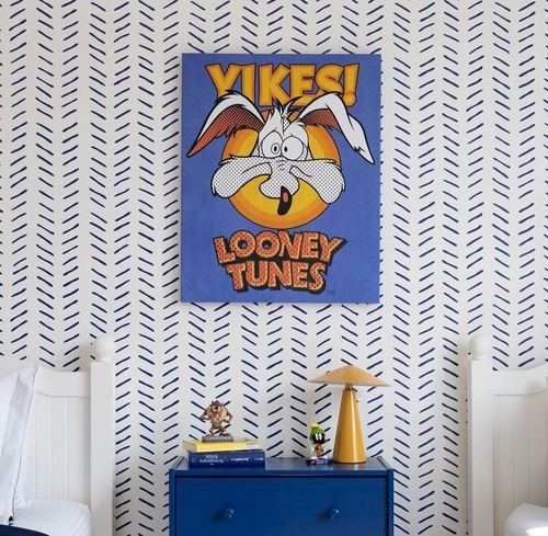 Kids bedroom with blue herringbone wallpaper, Looney Tunes canvas, blue dresser and mustard lamp
