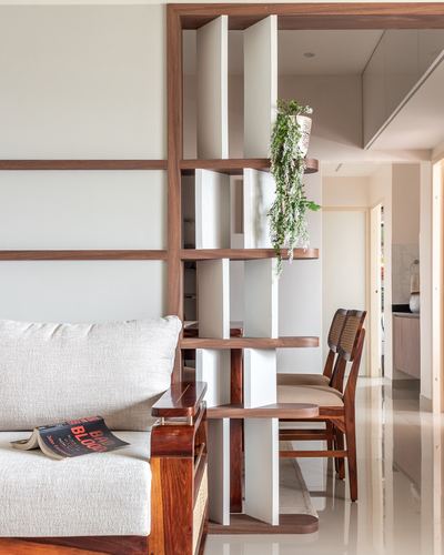 Wooden sculptural shelf divider between living room sofa and dining area with hanging plant
