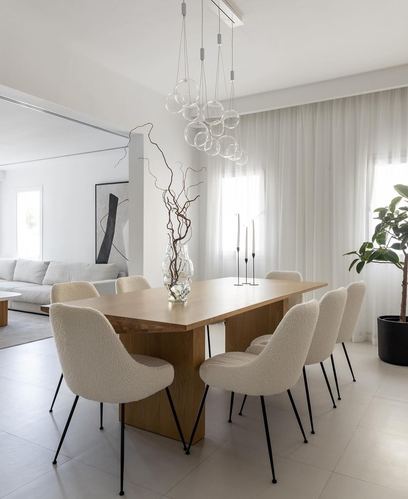 Minimalist dining room with wood table, boucle chairs, and glass bubble chandelier
