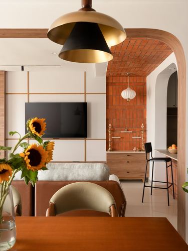 Dining table with sunflowers opens through brick archway to kitchen and living area