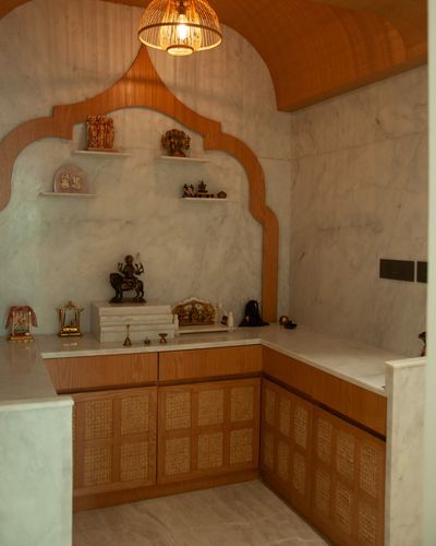 Pooja room with arched marble niche, brass idols, cane cabinetry and hanging lantern light