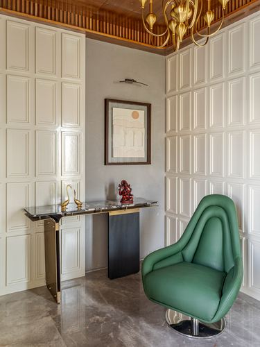 Foyer with white paneled walls, marble console with swan sculptures, and emerald green swivel chair