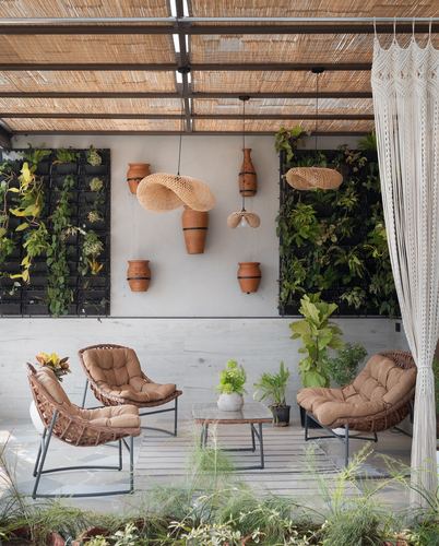 Outdoor terrace with rattan chairs, hanging pendant lights, terracotta pots and green wall