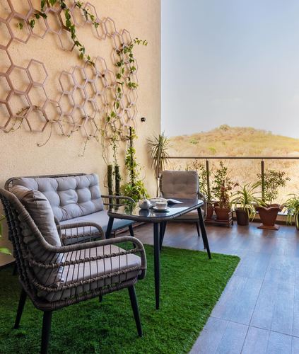 Balcony seating with rattan chairs, glass table, turf flooring and hill view