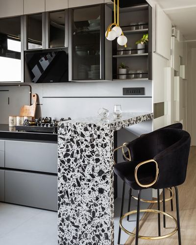 Kitchen with black-and-white terrazzo island, black velvet bar stools, and gold pendant lights