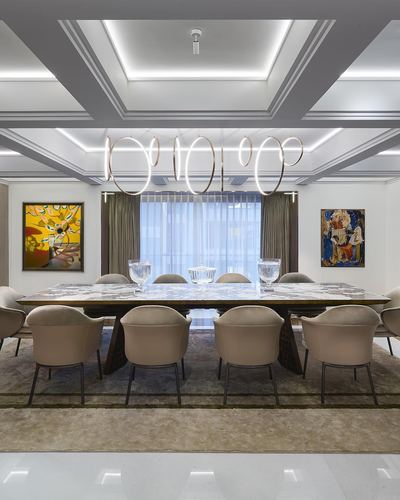 Formal dining room with long marble table, beige chairs, ring chandelier and coffered ceiling