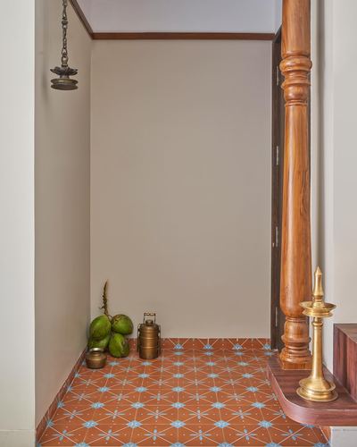 Foyer corner with turned wooden pillar, brass lamp, coconuts on patterned terracotta tile floor