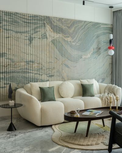 Cream boucle sofa with green cushions against a fluted marble wall in a Mumbai living room