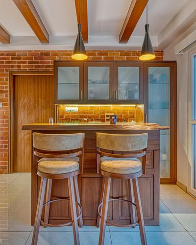 Kitchen bar counter with brick wall, wooden stools, and pendant lights over live-edge counter