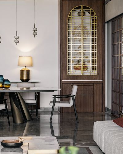 Dining area with marble table, brass lamp, and arched brass-grille wooden cabinet door