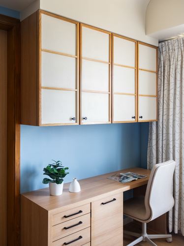 Wall-mounted paneled cabinets above a wooden desk with chair against a blue accent wall