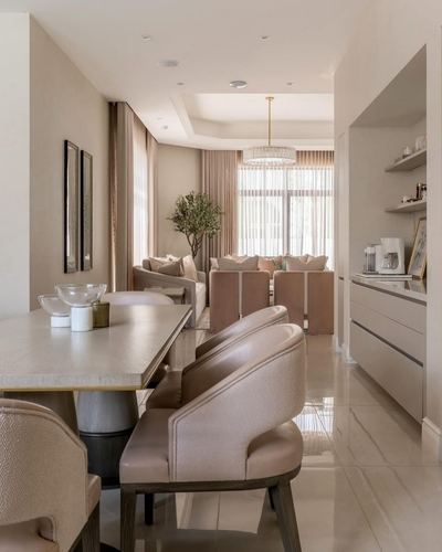Open-plan dining, kitchenette and living area in soft pink and beige tones with polished floor