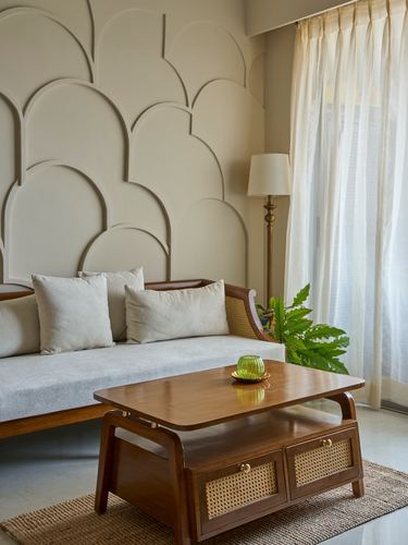 Living room corner with scalloped textured wall, cane-and-wood sofa, and wooden coffee table with cane drawers
