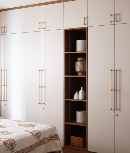 Floor-to-ceiling wardrobe with brass handles and an open wood-lined display niche in a bedroom