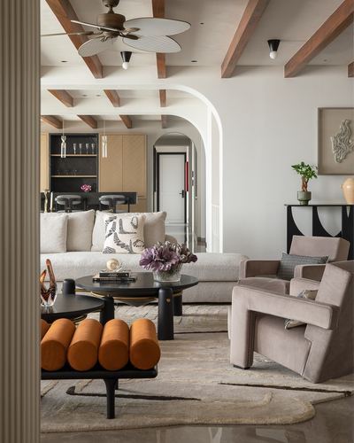 Living room with exposed beam ceiling, arched doorway, bouclé sofa and orange bolster bench