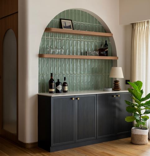 Arched green tiled bar niche with wooden shelves above a black fluted cabinet