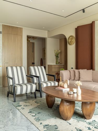 Living room with striped armchairs, carved wood coffee table, and arched wooden niche