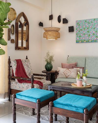 Eclectic living room with carved wooden armchair, turquoise ottomans, and arched mirror
