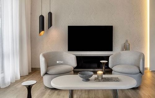 Monochrome living room with two curved grey armchairs facing an oval coffee table and TV wall