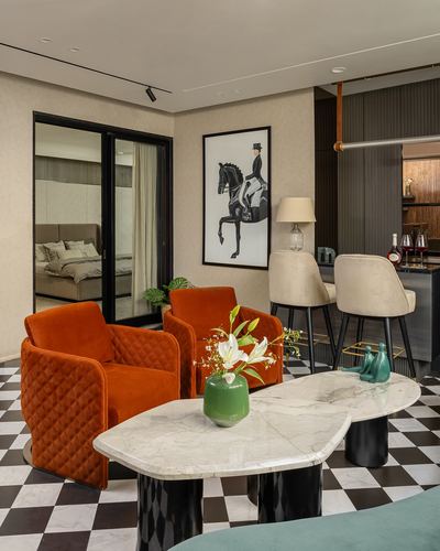Living room with orange velvet armchairs, checkerboard floor, and marble coffee tables beside a bar nook
