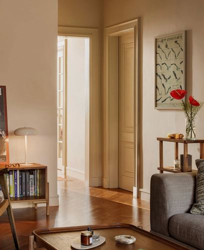 Warm living room with herringbone floor, panelled doors, console table with red poppies and framed art